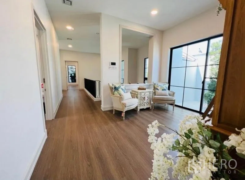 Detached House for rent or sale in Saphan Sung, Bangkok - Upstairs landing with seating nook and floor-to-ceiling black-framed windows.