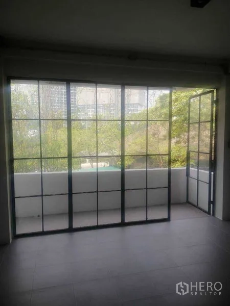 Shophouse for rent in Khlong Toei, Bangkok - Balcony with sliding glass doors open to a leafy neighborhood view.