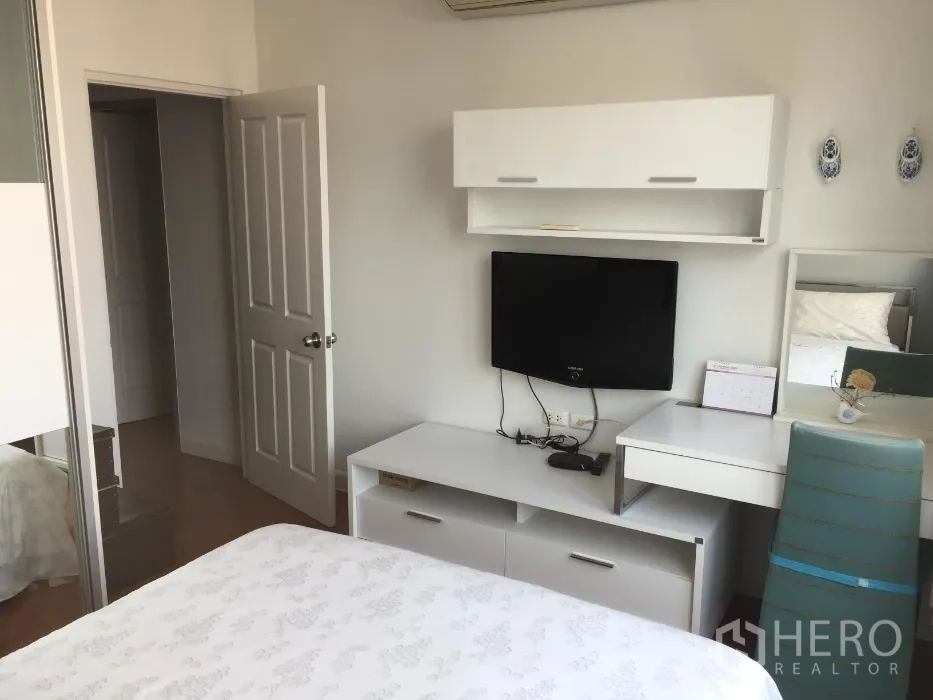 公寓 出租或出售在Khlong Toei, Bangkok - 明亮卧室，白色家具、壁挂电视、书桌与推拉衣柜。