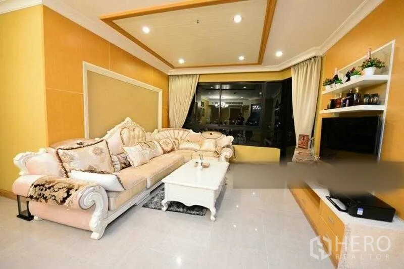 Condominium for rent in Bang Kho Laem, Bangkok - Elegant living room with plush sectional sofa, TV wall unit and large city-view window.