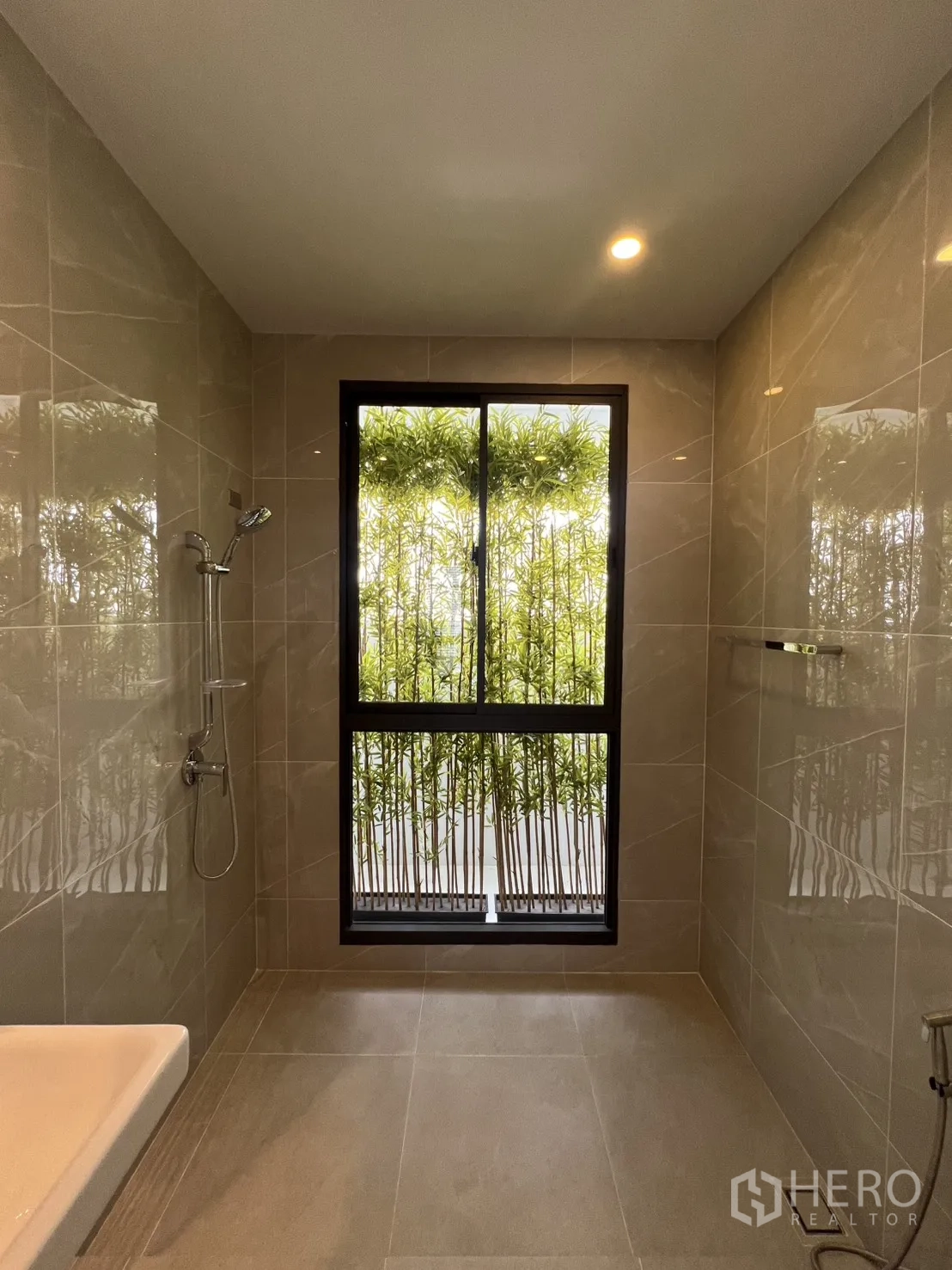 Townhouse for rent in Mueang Samut Prakan, Samut Prakan - Tiled bathroom with walk-in shower and large window overlooking bamboo greenery.