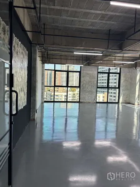 Office Space for rent - Glass entry door to an industrial-style office with city-facing windows and reflective flooring.