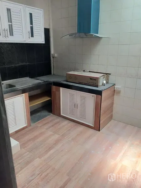 Detached House for rent in Watthana, Bangkok - Fitted kitchen with cabinets, sink, countertop space and a chimney hood over the cooktop area.