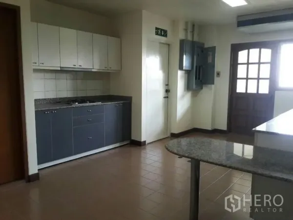 Condominium for rent in Pathum Wan, Bangkok - Kitchen view showing ample cabinetry, granite breakfast bar, utility panels, and doors to service areas.