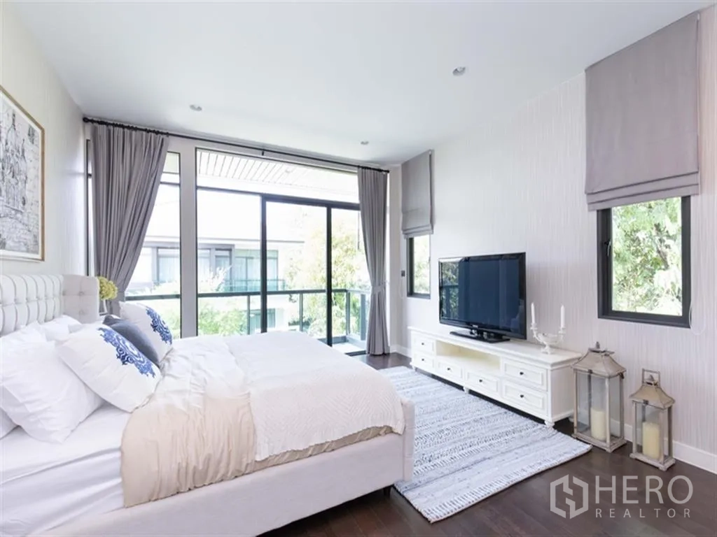 Detached House for rent in Bang Kapi, Bangkok - Spacious master bedroom with large windows, TV console, soft furnishings, and balcony outlook.