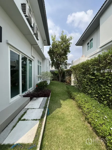 独立式住宅 出租在Prawet, Bangkok - 侧院草坪与踏步道，落地窗采光充足。