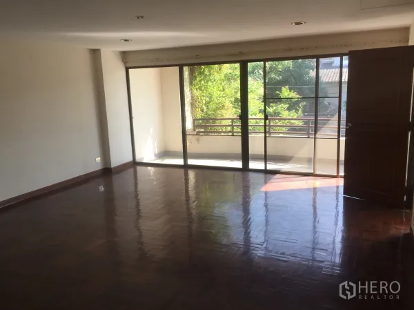 สำนักงานที่บ้าน ขายในWatthana, Bangkok - ห้องนั่งเล่นกว้าง ประตูกระจกบานเลื่อนออกสู่ระเบียง มองเห็นต้นไม้.