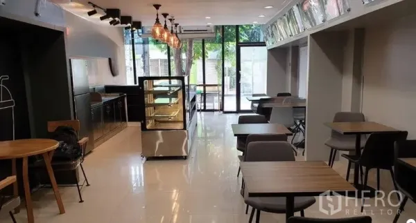 Shophouse for rent in Chatuchak, Bangkok - Open-plan shop interior facing the glass entrance, with counter pantry and illuminated display cabinet.