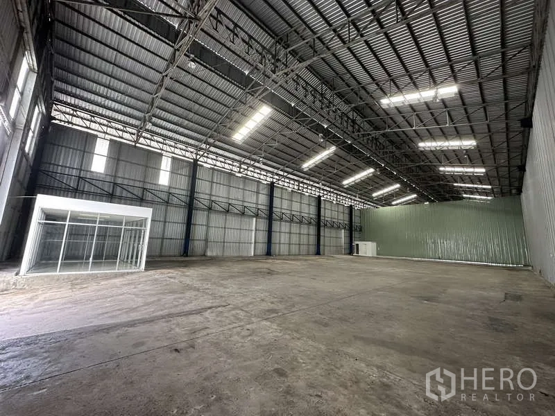 Warehouse for rent in Pak Kret, Nonthaburi - Spacious warehouse floor with LED lights and an office module along the side wall.