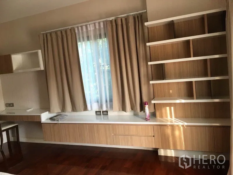 独立式住宅 出售在Khlong Toei, Bangkok - 卧室角落，内置书桌与置物架，米色窗帘与木地板。