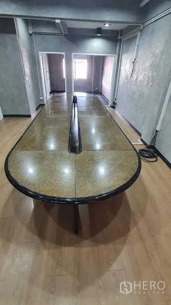 Office Space for rent or sale in Bueng Kum, Bangkok - Conference room with a long stone-top boardroom table, wood floor and concrete-finish walls.