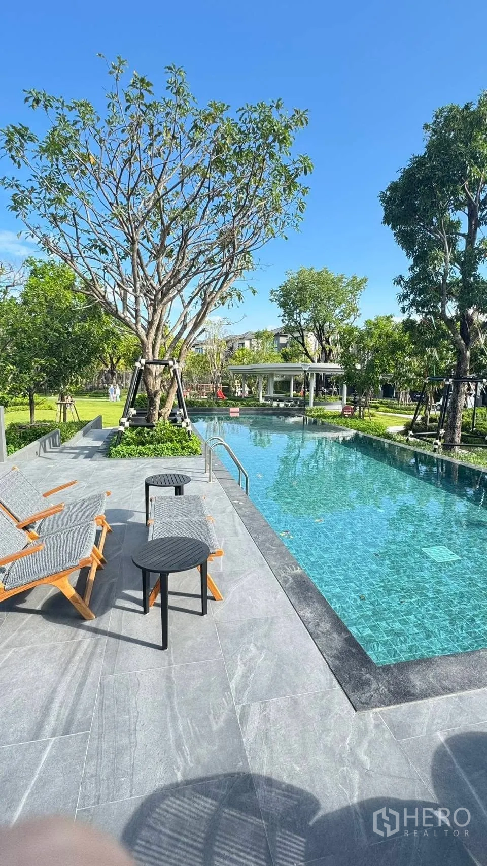 Townhouse for rent in Bang Phli, Samut Prakan - Communal swimming pool with sun loungers, trees, and landscaped gardens.
