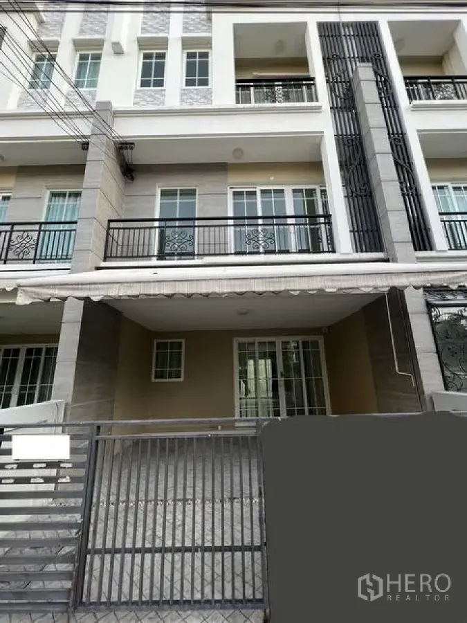 带办公室的家 出租或出售 - Bang Na 区多层住办两用楼外立面，带大门车位与阳台。