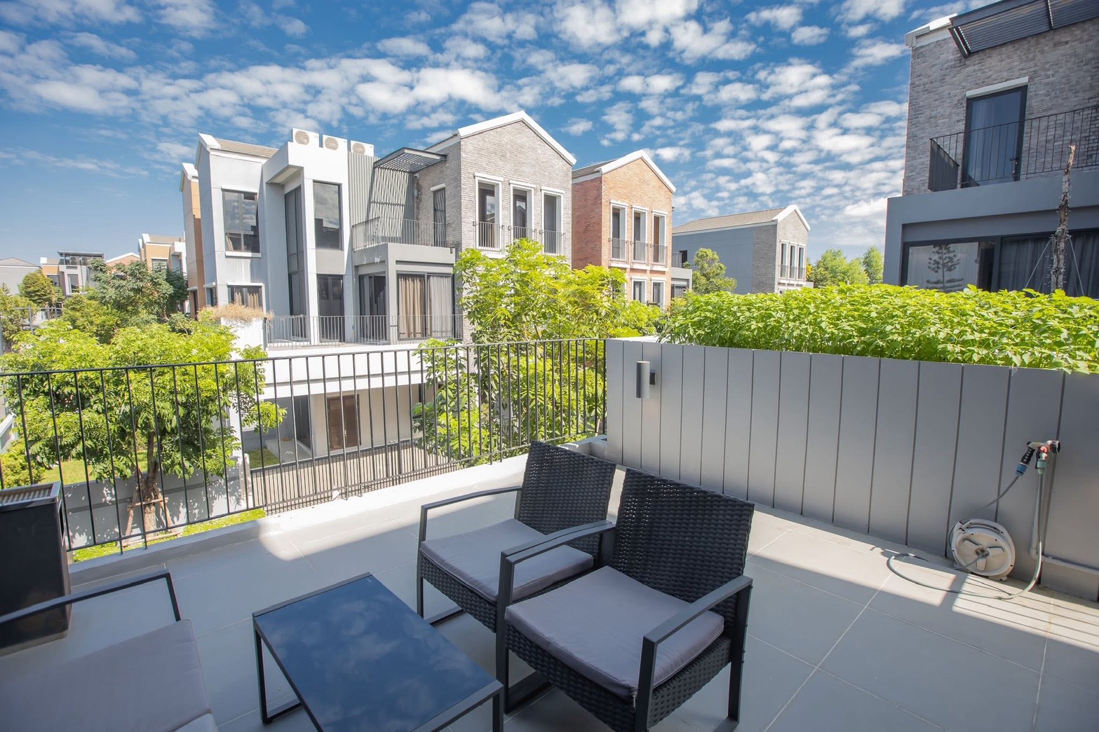 独立式住宅 出租在Lat Phrao, Bangkok - 阳台休闲区，可见周边现代住宅与郁郁葱葱的景观。