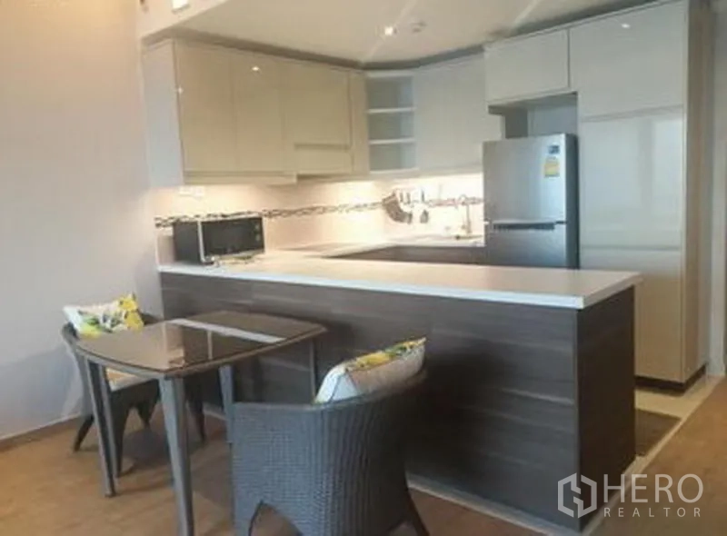 Condominium for sale in Sathon, Bangkok - Kitchen with dining nook, peninsula counter, refrigerator and a two‑seat table.