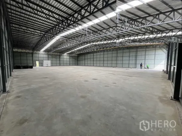 Warehouse for rent or sale in Pak Kret, Nonthaburi - Open-plan warehouse floor with wide loading access at the far end beneath steel framing.
