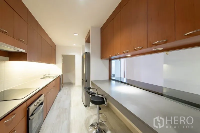 Condominium for rent - Sleek galley kitchen with ample cabinetry, oven, cooktop and long counter.