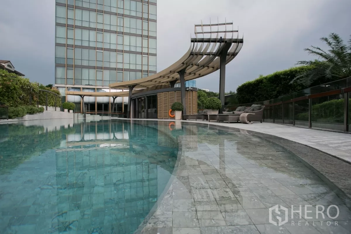 公寓 出租在Watthana, Bangkok - 室外泳池，弧形池畔、遮阳廊架与绿篱景观。