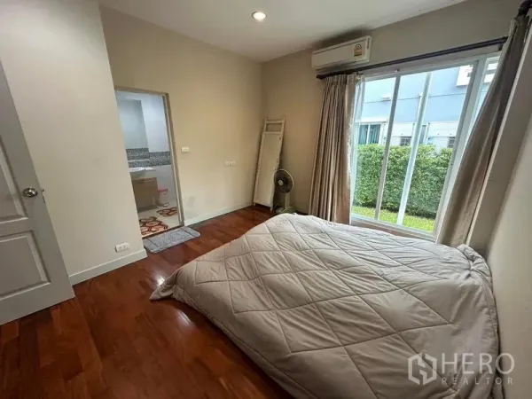 Detached House for sale in Saphan Sung, Bangkok - Cozy bedroom with wood flooring, large window to the garden and an ensuite doorway.