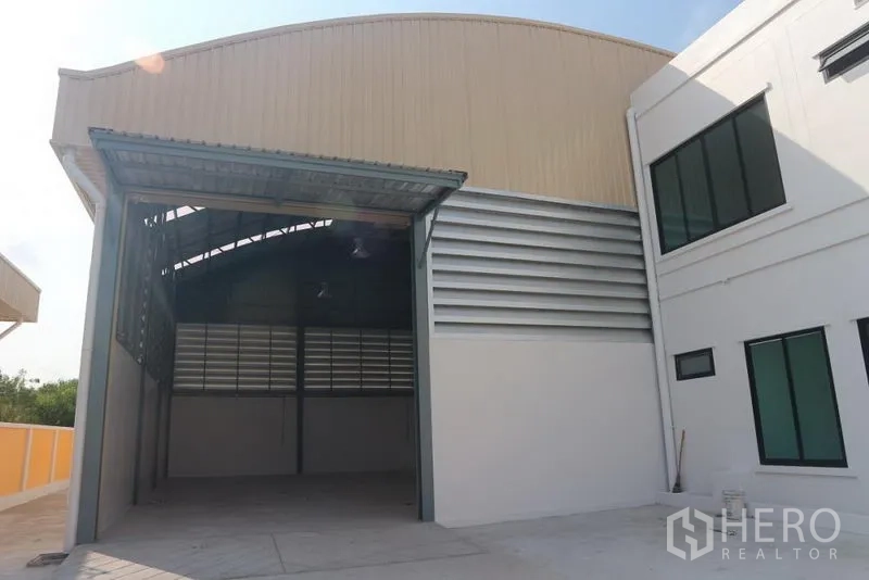 Factory for sale in Bang Pakong, Chachoengsao - Factory loading bay and warehouse entrance beside a two-storey office block.