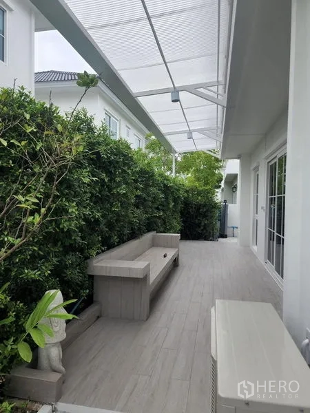 独立式住宅 出租在Bang Phli, Samut Prakan - 侧边有顶露台，内置长椅、瓷砖地面与私密绿篱。