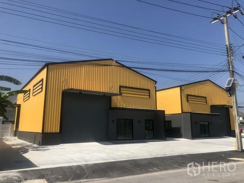 工厂 出租在Bang Yai, Nonthaburi - 并排黄色钢结构厂房，宽阔混凝土前院与装卸区。