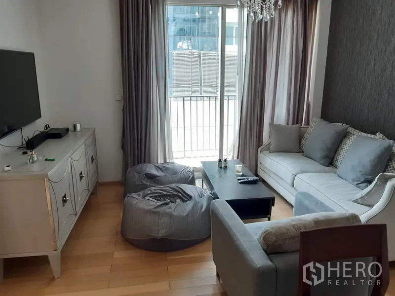 คอนโด ให้เช่าในKhlong Toei, Bangkok - ห้องนั่งเล่นสว่างเชื่อมระเบียง พื้นไม้ โซฟาและชั้นวางทีวี พร้อมประตูกระจกบานเลื่อน