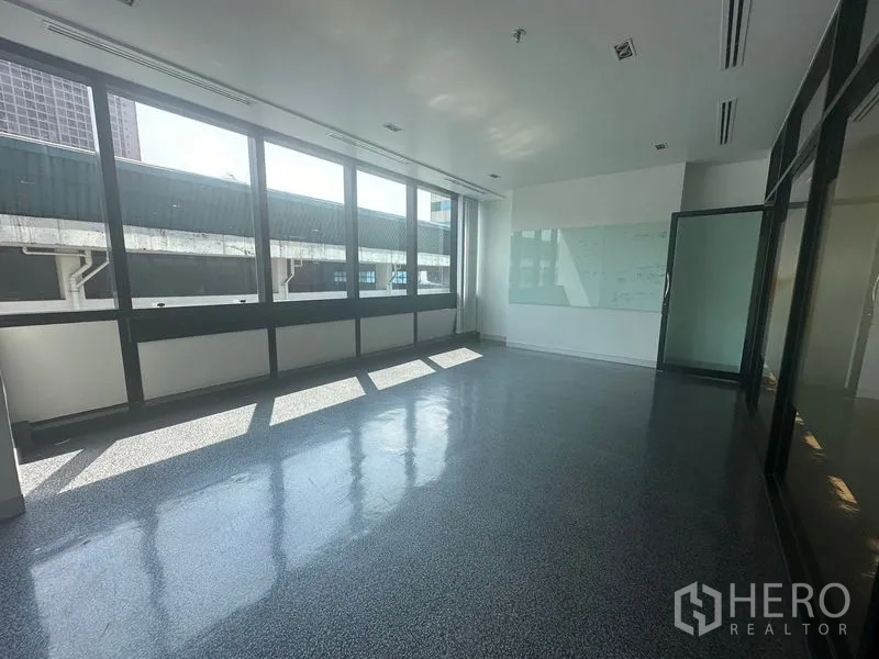 Office Space for rent in Khlong Toei, Bangkok - Private office with long windows, a whiteboard and a sliding glass door.
