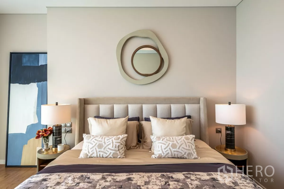 Condominium for rent or sale in Pathum Wan, Bangkok - Close-up of plush bed with patterned pillows and circular wall art.