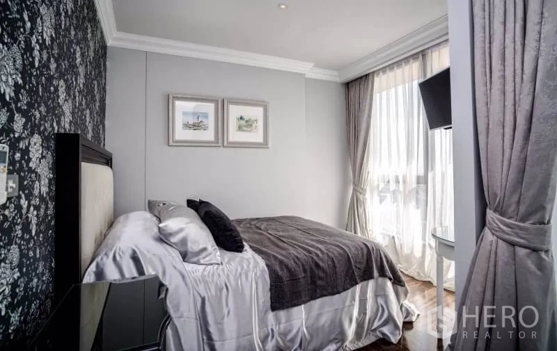 Condominium for rent or sale in Khlong Toei, Bangkok - Second bedroom with patterned accent wall, double bed and sheer curtains.