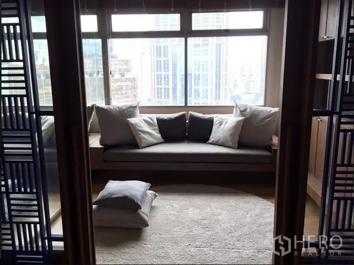 Condominium for rent in Watthana, Bangkok - Cozy window seat lounge with large windows and Bangkok skyline view.