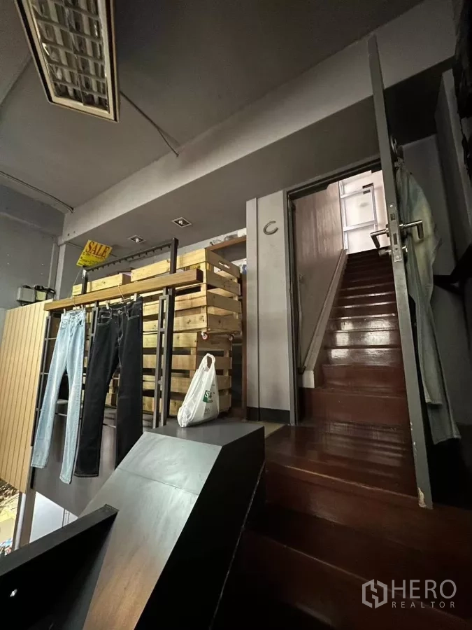店屋 出租在Ratchathewi, Bangkok - 店内夹层，木楼梯、服装挂架和阁楼式储物区。