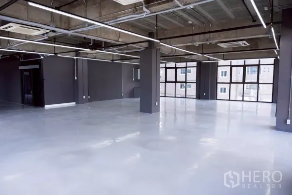 Office Space for rent - Spacious work area with exposed ducting, split-type ceiling AC and full-height glazing.