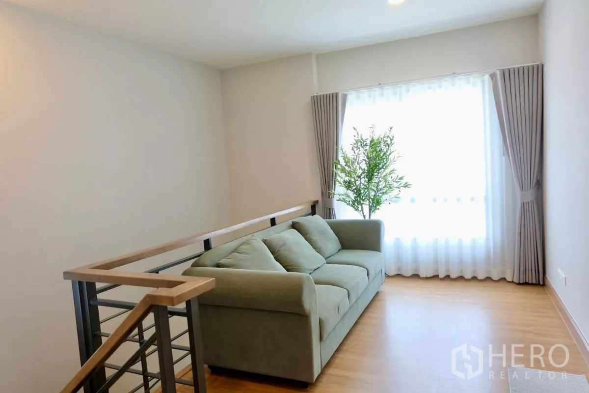 Detached House for sale in Bang Phli, Samut Prakan - Upstairs family area with green sofa, wood flooring, stair railing and a large window