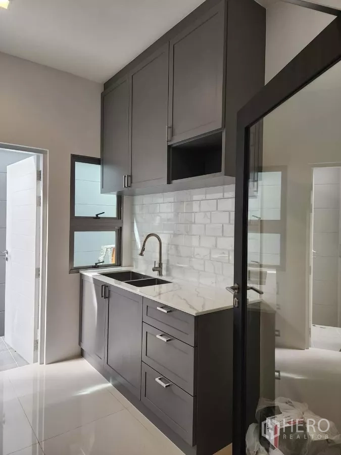 บ้าน ให้เช่าหรือขายในBueng Kum, Bangkok - มุมอ่างล้างจานครัวไทย ตู้แขวน ประตูกระจก และโซนซักล้าง