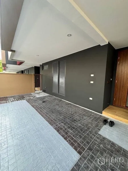 Townhouse for rent - Covered carport and front porch with dark facade and wood front door.