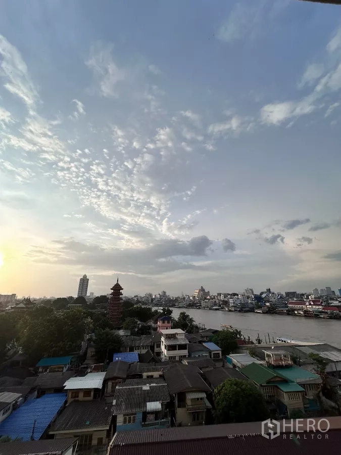 คอนโด ให้เช่าในKhlong San, Bangkok - ทิวทัศน์แม่น้ำเจ้าพระยาและสกายไลน์ยามเย็น พร้อมเจดีย์และชุมชนริมน้ำ