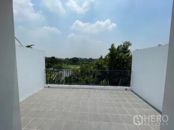 Townhouse for rent in Bang Kapi, Bangkok - Spacious tiled rooftop terrace with metal railing overlooking green views and blue sky.