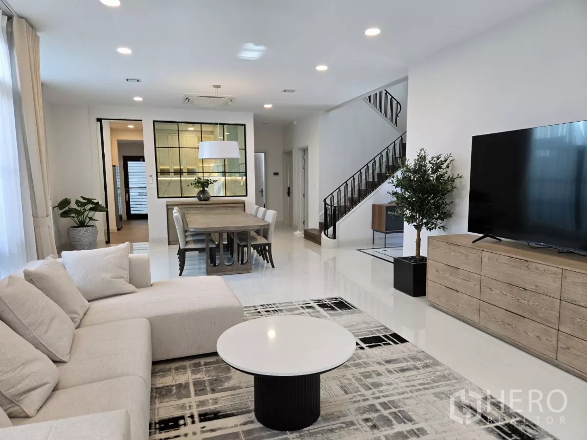 Detached House for rent in Saphan Sung, Bangkok - Bright open‑plan living and dining area with sofa, TV and staircase.