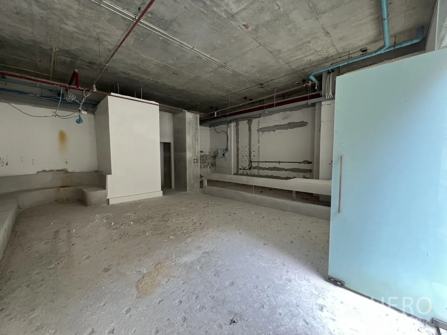 Retail Space for rent in Khlong Toei, Bangkok - Front zone with open glass door, unfinished walls and electrical rough-ins.