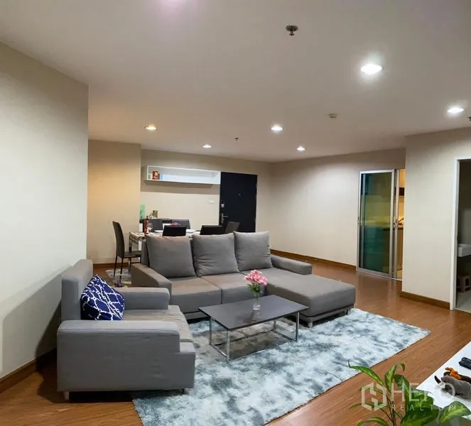 Condominium for rent - Spacious living room with gray sectional sofa, work desk, and warm lighting.