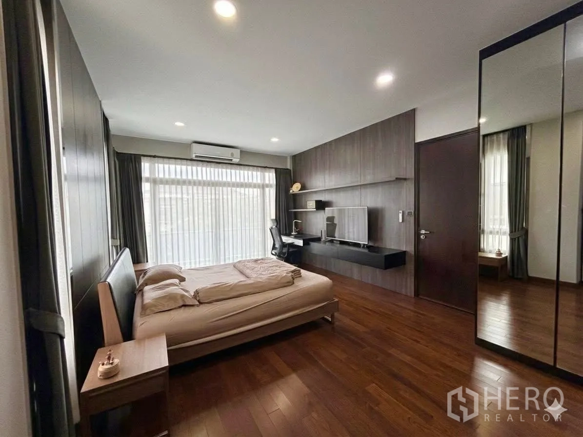 Detached House for rent in Bang Phli, Samut Prakan - Large bedroom with bed, TV wall unit and floor-to-ceiling window.