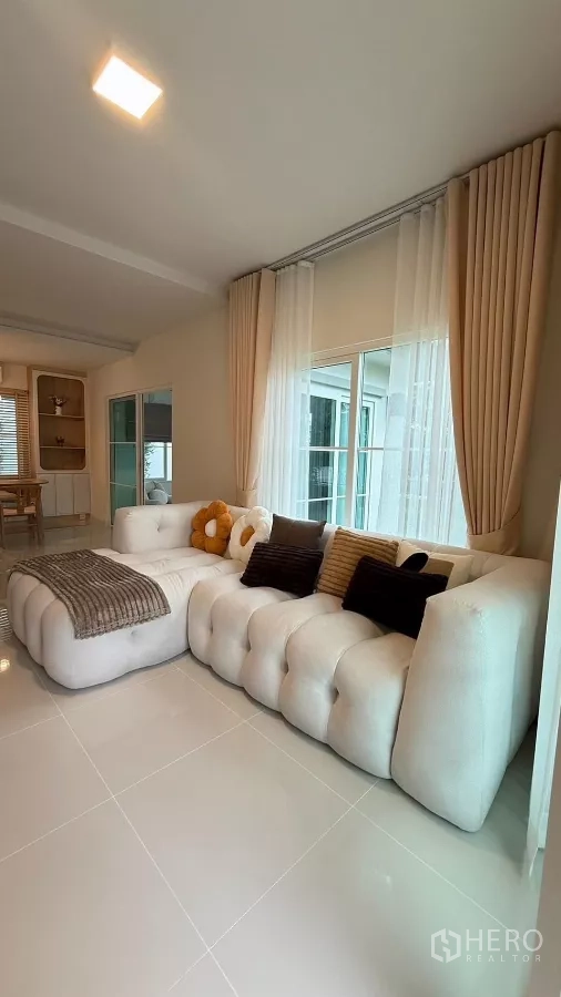 บ้าน ให้เช่าในBang Phli, Samut Prakan - พื้นที่นั่งเล่นกว้างพร้อมโซฟาตัวใหญ่และผ้าม่านสูงจรดเพดาน.