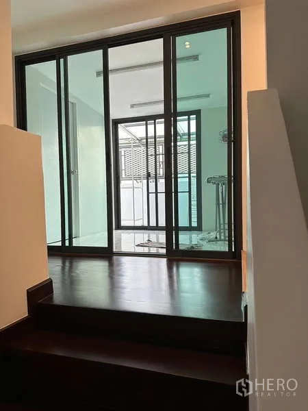 Townhouse for rent in Yan Nawa, Bangkok - Landing area with steps and sliding glass doors to a utility balcony.