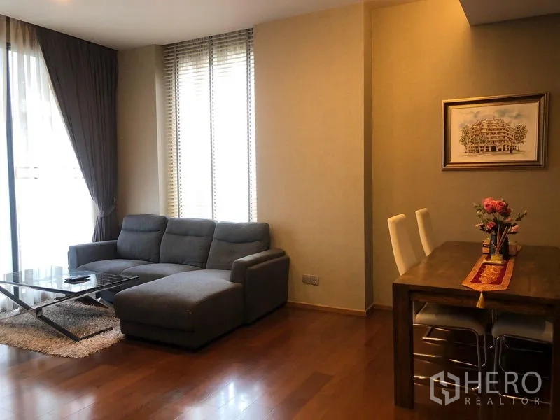 公寓 出租或出售在Watthana, Bangkok - 客餐厅一体，灰色L型沙发与玻璃茶几。