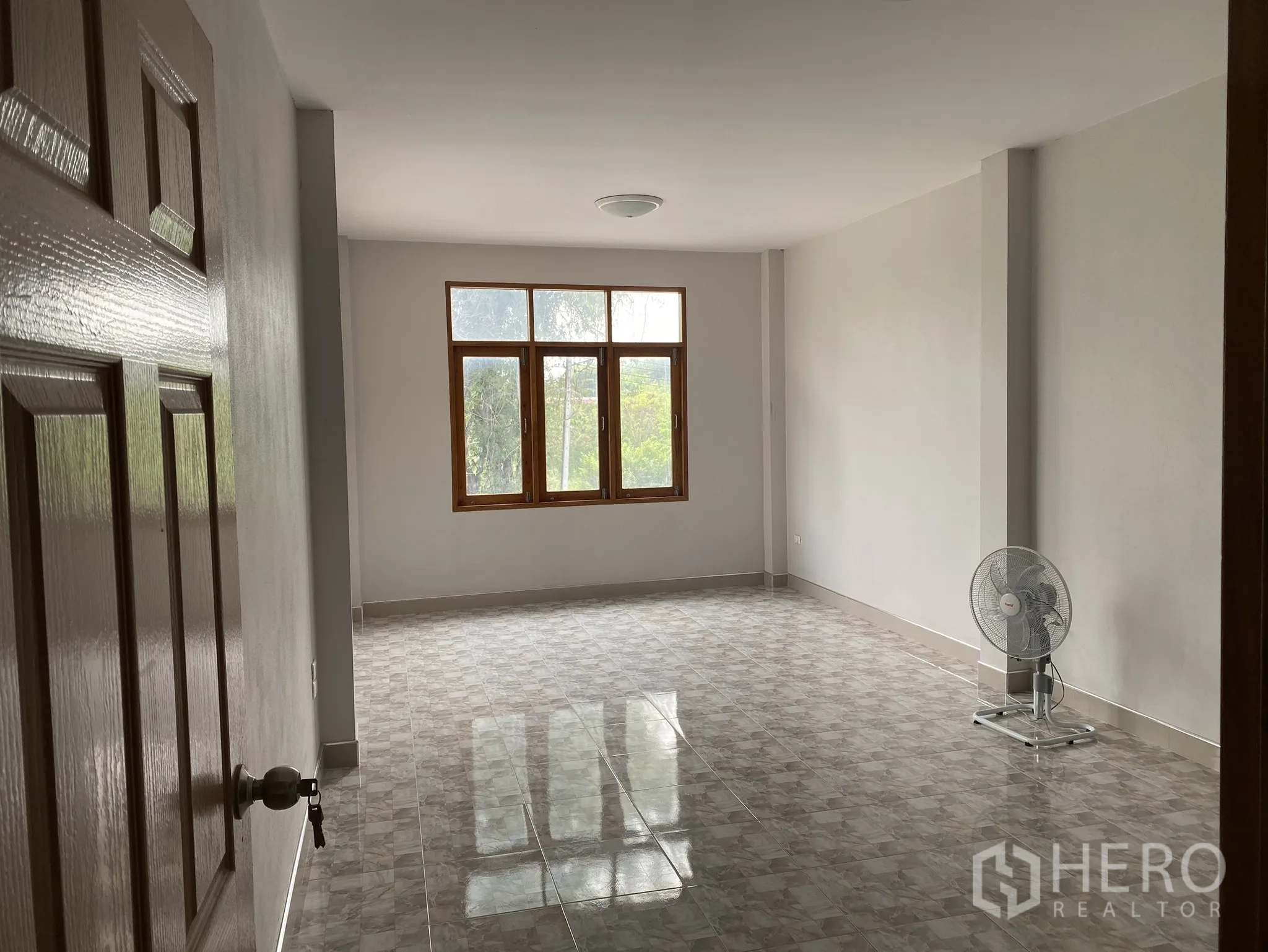 Factory for sale in Mueang Chon Buri, Chon Buri - Empty tiled room with window and stand fan.