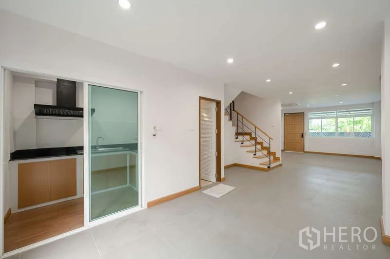 ทาวน์เฮาส์ ขายในLat Phrao, Bangkok - ห้องนั่งเล่นโปร่งสว่าง ฝ้าไฟดาวน์ไลท์ พร้อมบันไดและหน้าต่างบานใหญ่