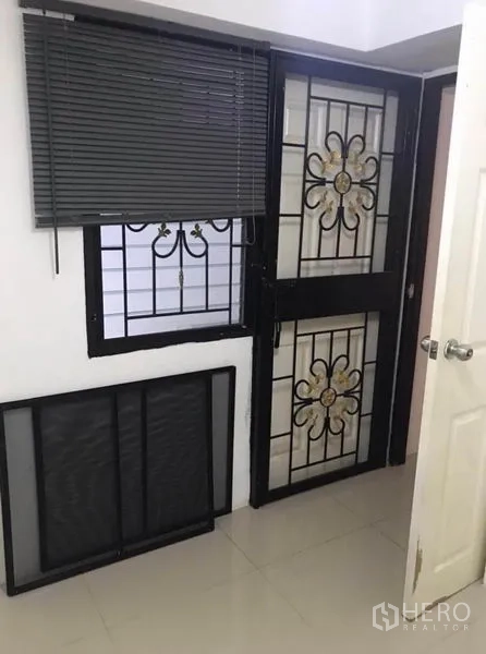 Townhouse for rent in Wang Thonglang, Bangkok - Security door and window with decorative wrought-iron grills and blinds.