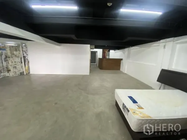 Retail Space for rent in Bangkok - Spacious rear area with low black ceiling, concrete floor, and service counter suitable for storage or workspace.