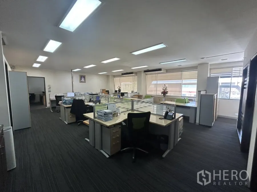 สำนักงาน ให้เช่า - พื้นที่ทำงานแบบเปิด โต๊ะทำงานหลายชุด พื้นพรมและหน้าต่างบานใหญ่รับแสงธรรมชาติ